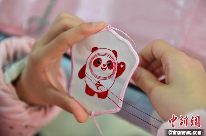 圖為一名小學(xué)生正在繡制2022年北京冬奧會(huì)吉祥物“冰墩墩”形象?！∮髟屏?攝