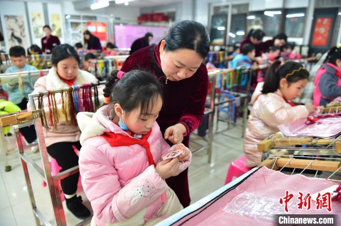 江西省級(jí)非遺豫章繡傳承人手把手指導(dǎo)小學(xué)生繡制2022年北京冬奧會(huì)吉祥物“冰墩墩”形象。　喻云亮 攝