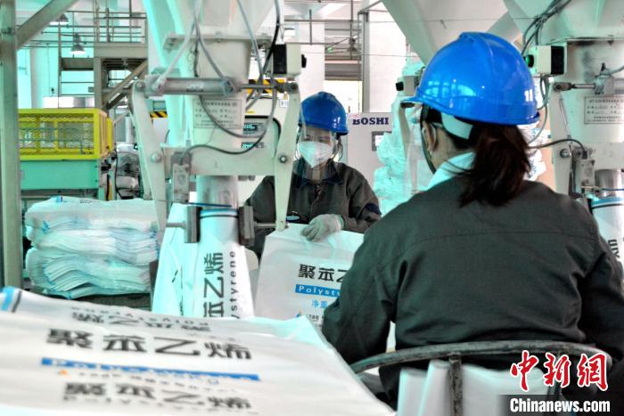 工人在生產(chǎn)線上包裝聚苯乙烯產(chǎn)品?！×趾霔v 攝