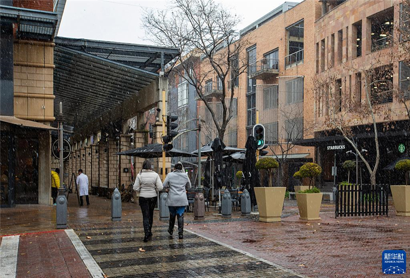 7月10日，在南非約翰內(nèi)斯堡一處商業(yè)區(qū)，人們在雪中行走。新華社記者 張譽東 攝