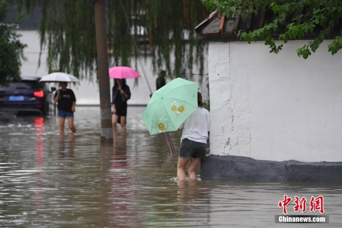 7月31日，市民行走在雨中的北京房山區(qū)瓦窯頭村。北京市氣象臺當(dāng)日10時發(fā)布分區(qū)域暴雨紅色預(yù)警信號。北京市水文總站發(fā)布洪水紅色預(yù)警，預(yù)計當(dāng)日12時至14時，房山區(qū)大石河流域?qū)⒊霈F(xiàn)紅色預(yù)警標(biāo)準(zhǔn)洪水。<a target='_blank' href='/'><p  align=