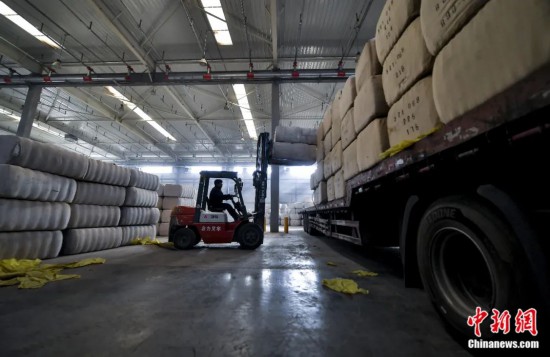 新疆喀什綜合保稅區(qū)，喀什啟路國際貿易有限公司的倉庫內，工人正在裝載從塔吉克斯坦和烏茲別克斯坦進口的棉花。劉新攝