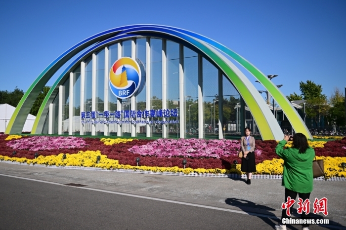 10月15日，北京，工作人員在國家會(huì)議中心外的第三屆“一帶一路”國際合作高峰論壇景觀布置前拍照留念。當(dāng)日，位于國家會(huì)議中心的第三屆“一帶一路”國際合作高峰論壇新聞中心啟動(dòng)試運(yùn)行。據(jù)悉，第三屆“一帶一路”國際合作高峰論壇將于10月17日至18日在北京舉行。<a target='_blank' href='/'><p  align=