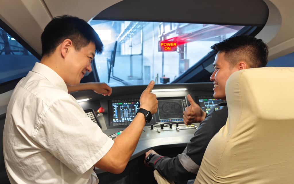 8月25日，在印度尼西亞萬隆的雅萬高鐵德卡魯爾動車所內(nèi)，中國師傅穆振（左）在向印尼火車司機塞蒂亞萬講解動車組出庫前的上電作業(yè)。