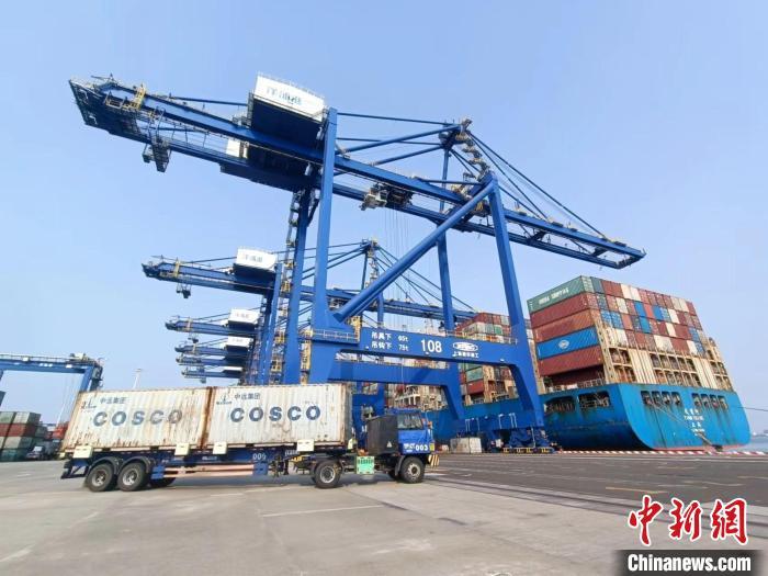 圖為海南洋浦國際集裝箱碼頭，卡車將集裝箱從后方堆場(chǎng)運(yùn)往碼頭裝卸區(qū)。　張?jiān)潞?攝