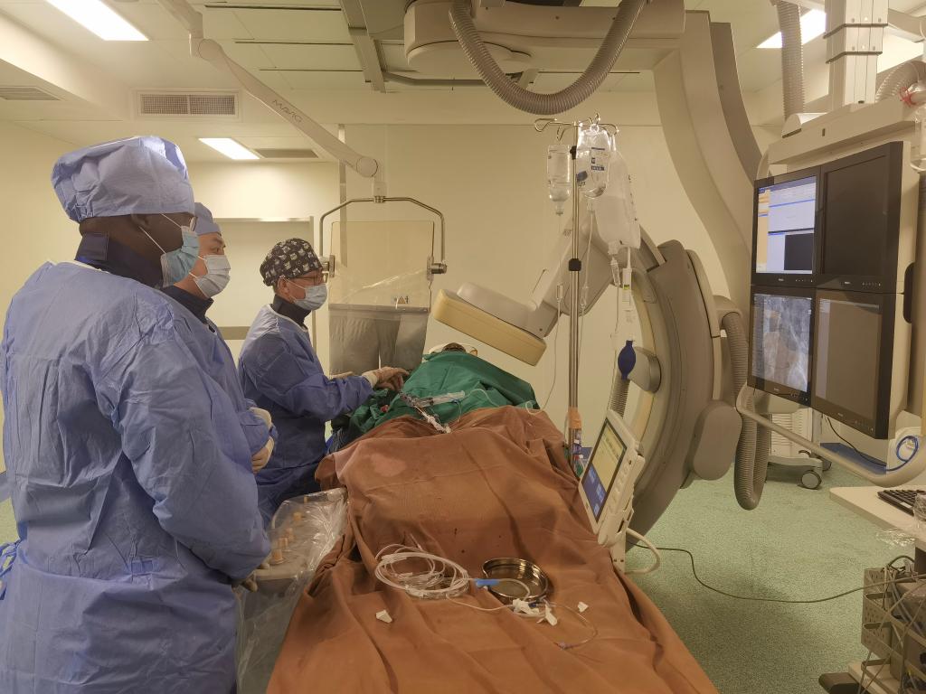 中國第29批援幾內(nèi)亞醫(yī)療隊(duì)隊(duì)員、首都醫(yī)科大學(xué)附屬北京天壇醫(yī)院心內(nèi)科副主任醫(yī)師王汝朋（右一）正在給患者做手術(shù)。（北京天壇醫(yī)院供圖）
