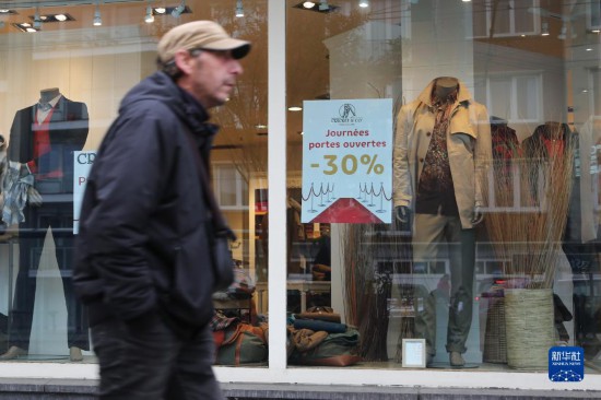   10月31日，一名男子從比利時(shí)布魯塞爾一家貼有打折信息的店鋪前走過(guò)。新華社記者 趙丁喆 攝