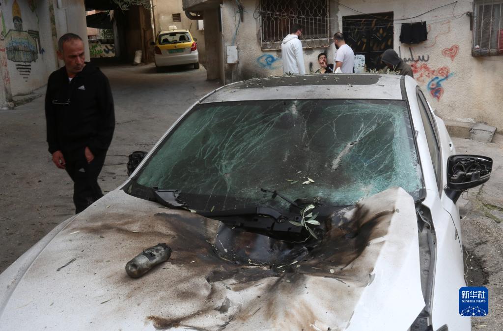 12月17日，在約旦河西岸城市圖勒凱爾姆附近的一處難民營，人們查看在沖突中損毀的車輛。新華社發(fā)（尼達(dá)爾·艾仕塔耶?dāng)z）