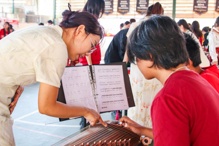 志愿者教師指導(dǎo)學(xué)生彈奏古箏?；顒又鬓k方供圖