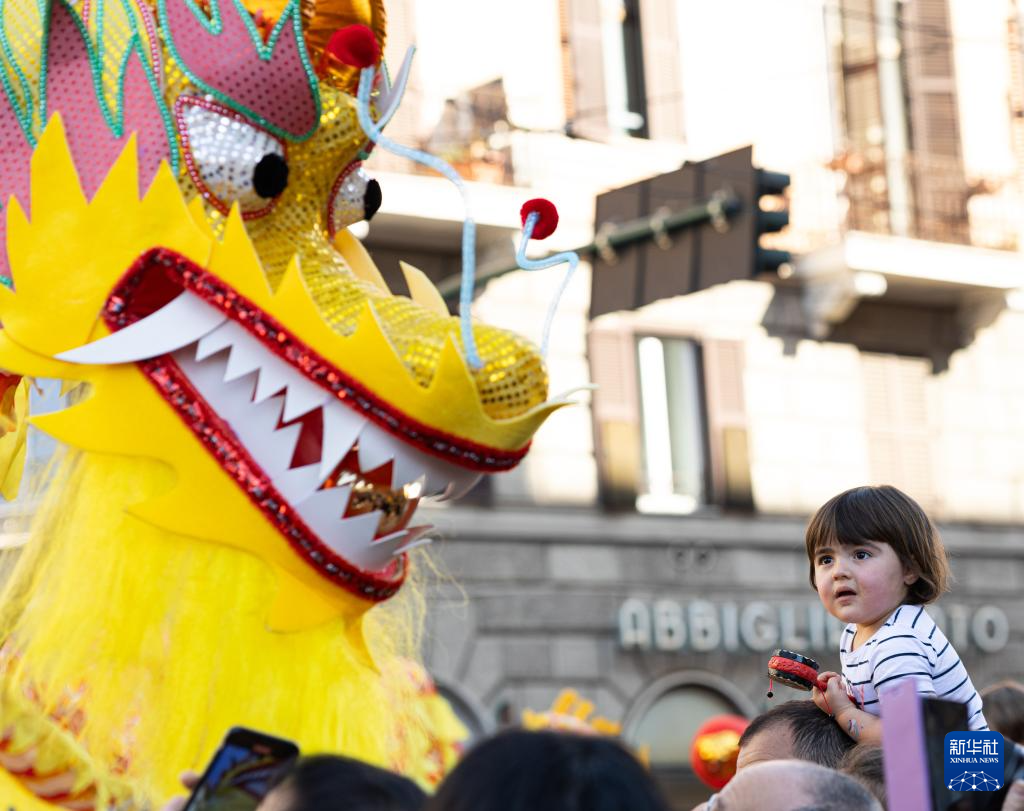 2月18日，在意大利羅馬，一名小朋友在彩妝巡游上觀看舞龍。新華社記者 李京 攝