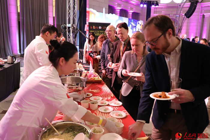當?shù)貢r間3月7日晚，華盛頓聯(lián)合車站廣場舉行駐美使團“使館主廚挑戰(zhàn)賽”。圖為當?shù)孛癖娫谥袊古_前體驗中國美食。人民網(wǎng)記者 李志偉攝