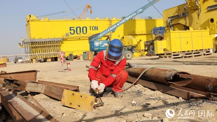 工人正在龍門吊吊裝現(xiàn)場切割金屬件。人民網(wǎng)記者管克江攝