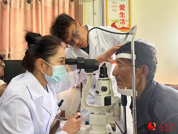 王紅英（左）和團(tuán)隊(duì)成員為達(dá)熱村村民檢查眼睛。人民網(wǎng)記者 杜燕飛攝