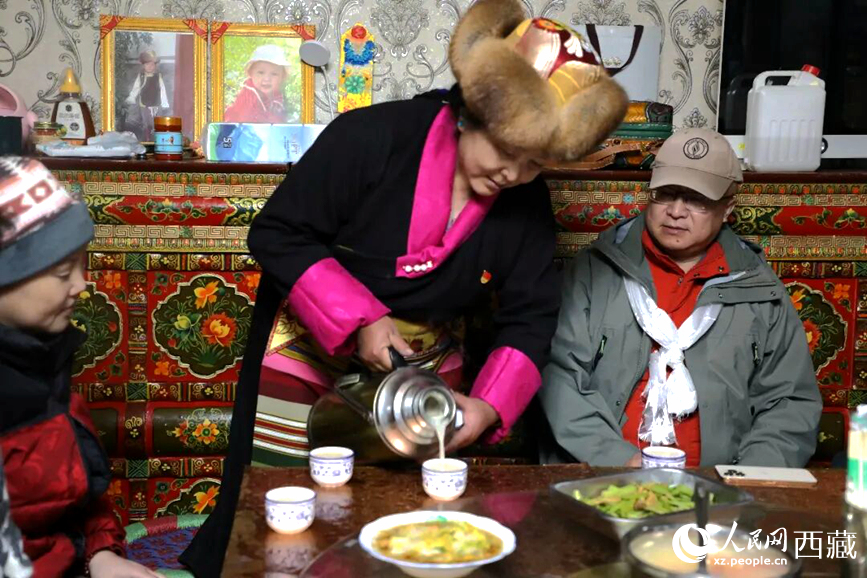 扎西曲登社區(qū)的居民在家中熱情招待遠道而來的游客。居民身著盛裝，為游客倒上熱騰騰的酥油茶，桌上擺放著切瑪與特色美食，賓主共話民族團結(jié)情誼。人民網(wǎng)記者 吳雨仁攝