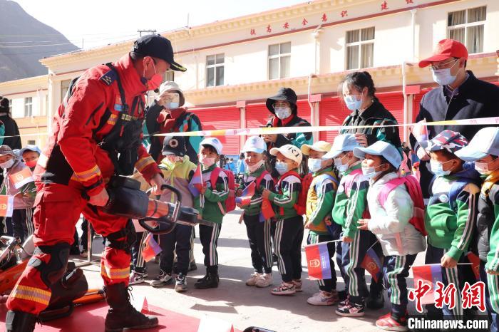 圖為消防指戰(zhàn)員為學(xué)生講解、演示先進救援裝備?！≮w琳 攝