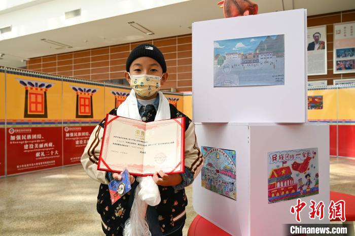 圖為一名獲獎學(xué)生與自己的繪畫作品合影。　趙朗 攝