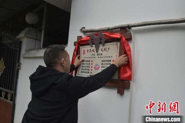 桂溪鎮(zhèn)渭溝村政府工作人員為“十星級文明戶”掛上牌匾。　楊勇 攝