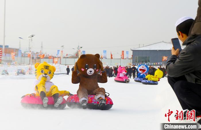 圖為臨夏市南龍鎮(zhèn)馬家莊村舉辦的鄉(xiāng)村文化旅游節(jié)上，游客穿著卡通服裝在體驗雪上飛碟項目。近年來，臨夏州形成了“春賞花、夏避暑、秋摘果、冬玩雪”的全季節(jié)旅游產(chǎn)品體系。(資料圖) 高展 攝