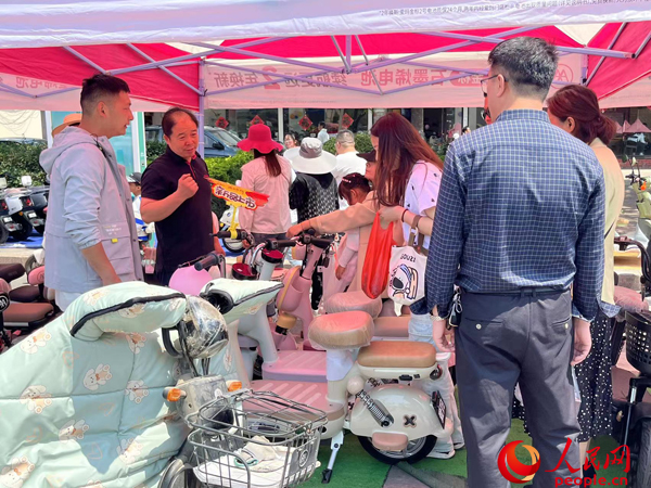 某電動(dòng)自行車品牌工作人員向消費(fèi)者介紹以舊換新相關(guān)情況。人民網(wǎng)記者 杜燕飛攝