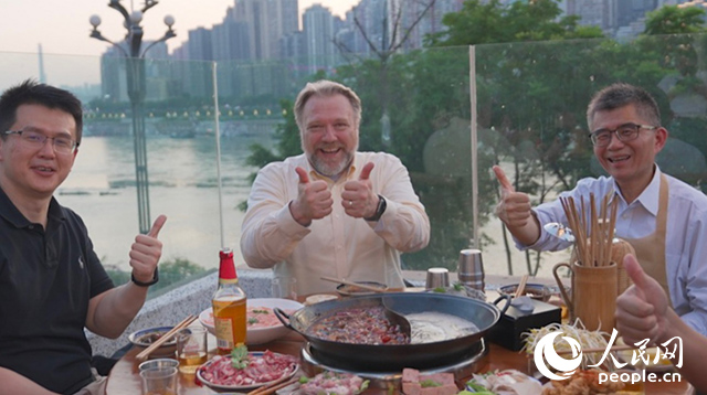 康寧顯示科技事業(yè)部全球拓建項(xiàng)目總監(jiān)軻寶華（中）和同事在重慶南濱路吃火鍋。人民網(wǎng)記者 蘇纓翔攝