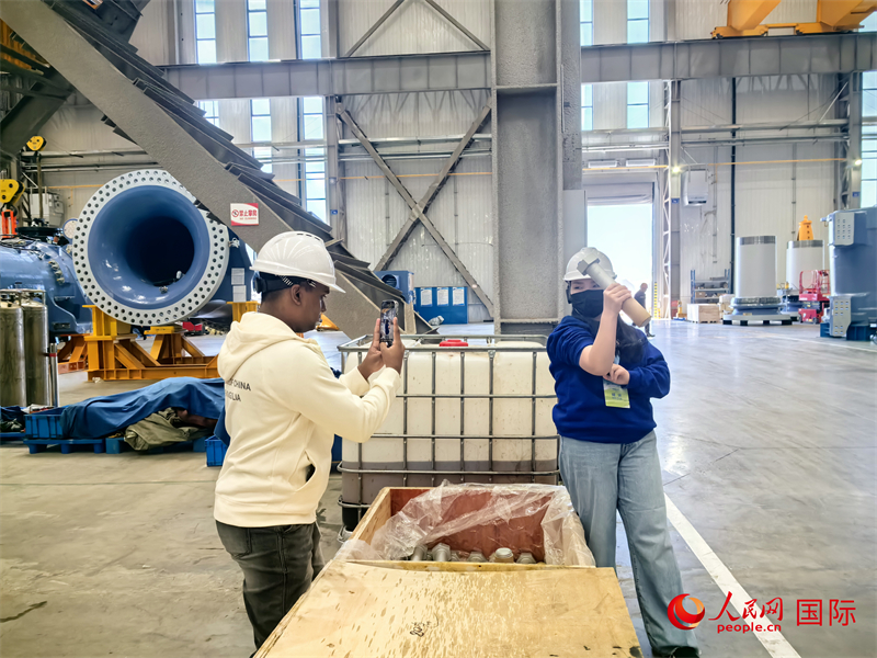 外媒記者掂量廠房?jī)?nèi)的巨型螺栓。人民網(wǎng) 楊春燕攝