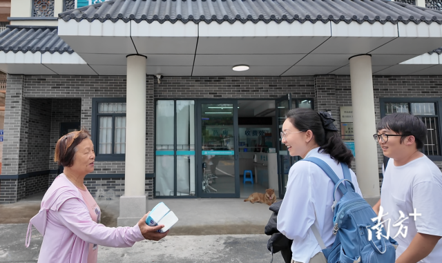 公共服務(wù)組成員王櫻潔（中）和張龍（右）在崖口村衛(wèi)生室前跟村民打招呼。