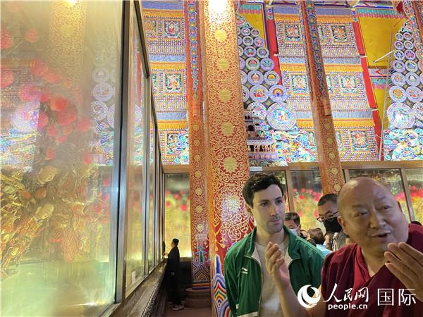 7月25日，省級(jí)非物質(zhì)文化遺產(chǎn)項(xiàng)目塔爾寺酥油花的代表性傳承人朋措堅(jiān)參（右）在塔爾寺酥油花館講解酥油花的制作過(guò)程。人民網(wǎng) 謝瑩攝