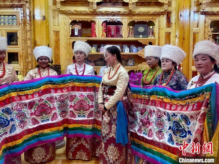 圖為女性展示村民自發(fā)繡制的“百米五彩哈達(dá)”?！±钣穹?攝