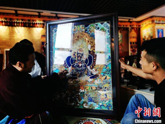圖為久美尖措(左)與徒弟們展示唐卡作品?！?zhí)砀?攝
