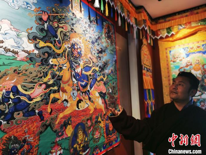 圖為久美尖措展示唐卡作品?！?zhí)砀?攝