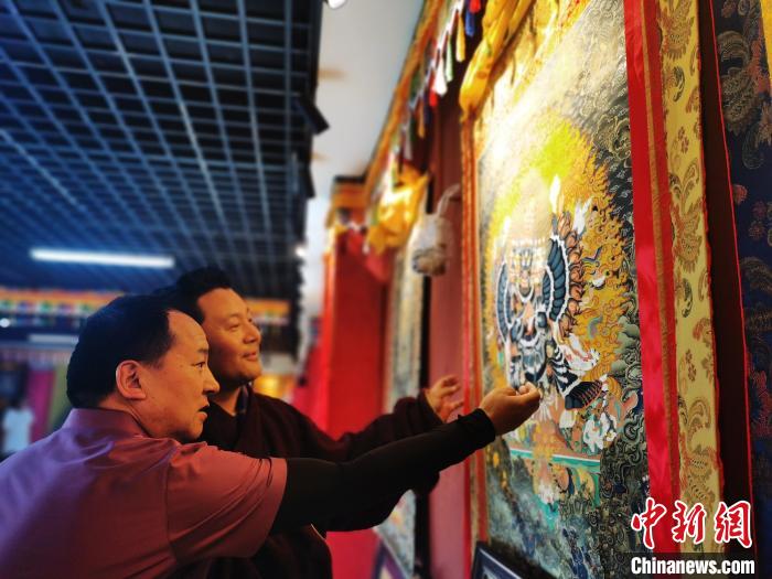 圖為久美尖措展示唐卡作品?！?zhí)砀?攝
