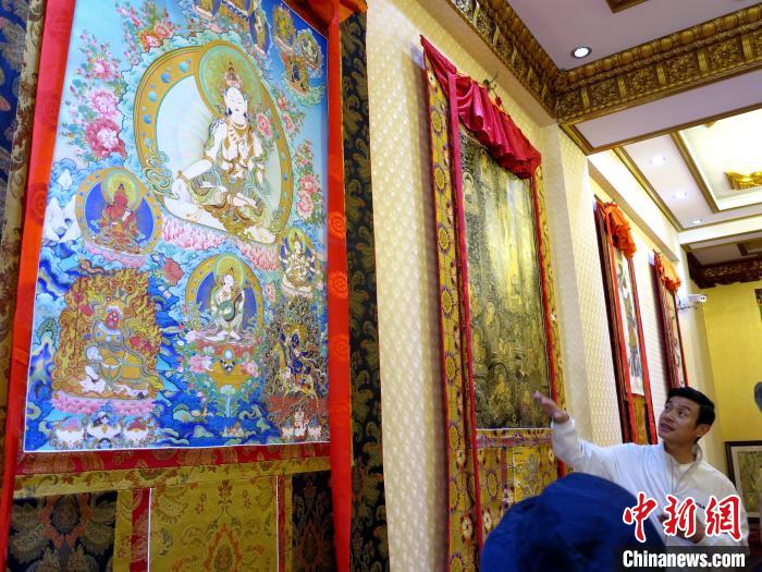 圖為完德尖措展示熱貢龍樹畫苑內(nèi)的唐卡?！?zhí)砀?攝