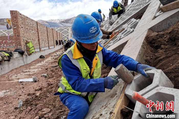 圖為光伏發(fā)電項(xiàng)目施工區(qū)工人在護(hù)坡鋪設(shè)空心磚?！±铍h 攝