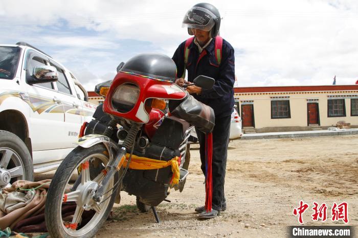 圖為白瑪準(zhǔn)備騎摩托車巡湖?！≮w朗 攝