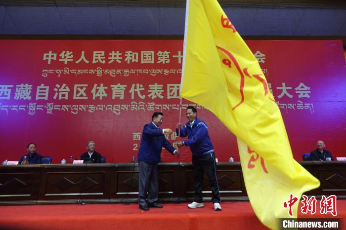 西藏自治區(qū)副主席甲熱·洛桑丹增授代表團(tuán)團(tuán)旗，西藏自治區(qū)體育局局長尼瑪次仁接旗?！∪轿木?攝