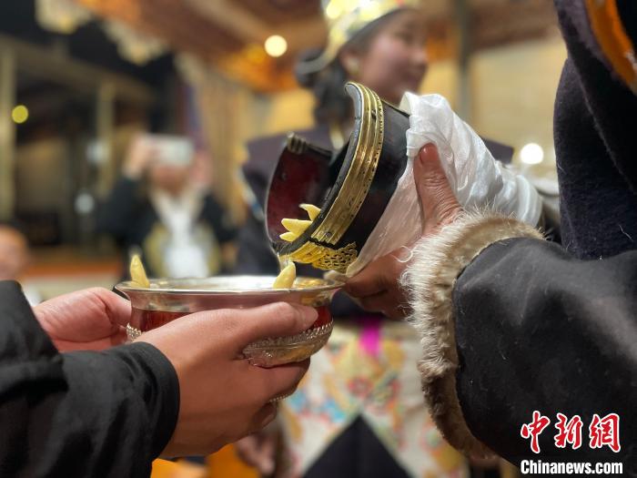 圖為主人在碗中斟滿青稞酒。　冉文娟 攝