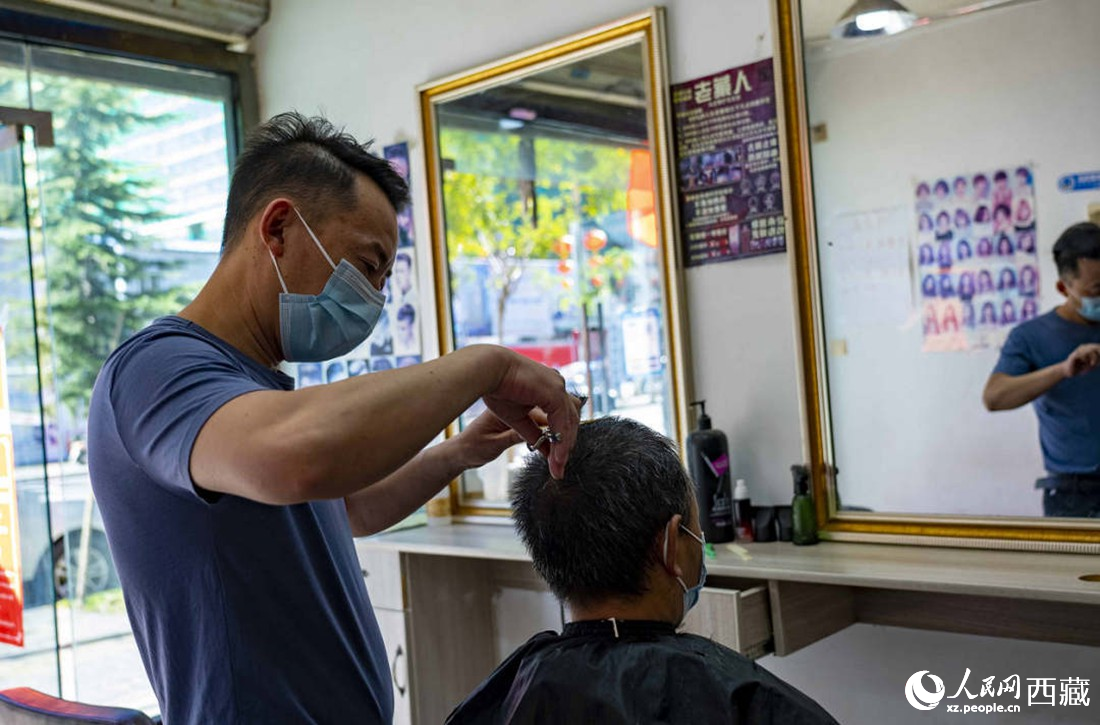 理發(fā)店老板為顧客理發(fā)。次仁羅布 攝
