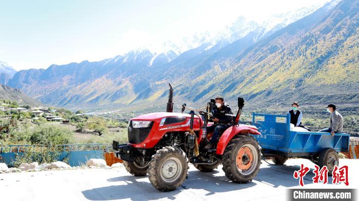 圖為工作人員將把加工完成的糌粑運(yùn)送至村民手中?！〖卫杩h融媒體中心供圖