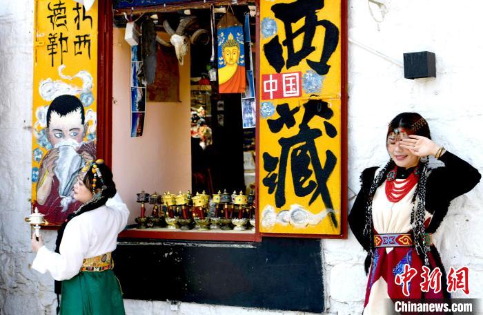 4月17日，游客身著藏式元素服裝在拉薩八廓街拍照留念。　李林 攝