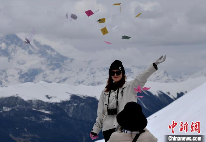 圖為5月14日，游客在西藏林芝色季拉山觀景臺拋灑“隆達”(風馬旗，藏族民眾的一種祈福方式)?！±盍?攝