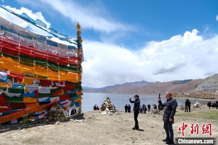 進(jìn)藏參訪嘉賓在羊湖畔拍攝經(jīng)幡?！〗w波 攝