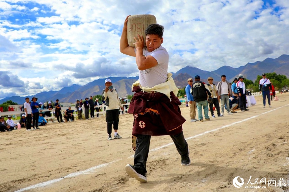 來自拉薩市當(dāng)雄縣的牧民選手將一塊150斤重的石頭扛在肩上飛奔。