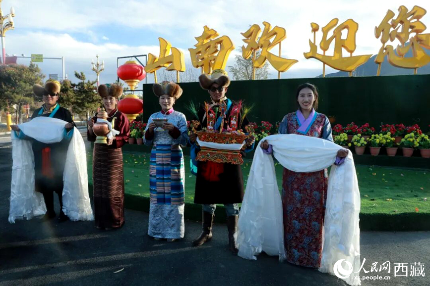 扎西曲登社區(qū)的居民在“山南歡迎您”標(biāo)志前，手持潔白哈達(dá)和切瑪，列隊(duì)迎接來(lái)自區(qū)內(nèi)外的游客，用最隆重的禮儀開(kāi)啟一場(chǎng)沉浸式藏歷新年民俗體驗(yàn)之旅。人民網(wǎng)記者 吳雨仁攝