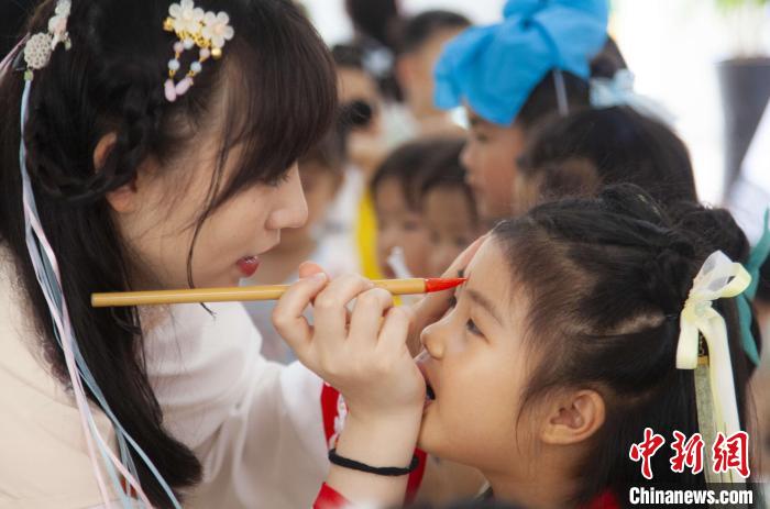 圖為老師在孩子們額頭上點上雄黃，驅(qū)邪辟禍?！《^生 攝