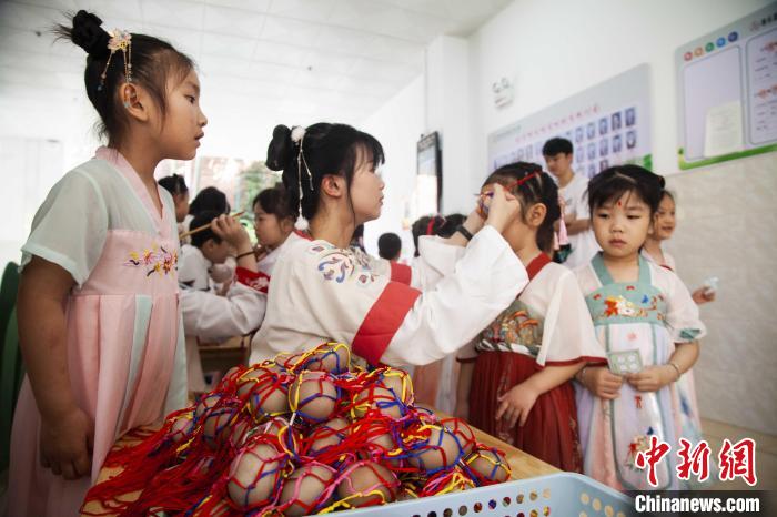 圖為幼兒園的老師們穿上漢服為小朋友們戴上彩蛋，寓意著幸福安康?！《^生 攝